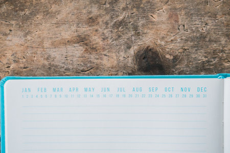 An opened blue textbook with date markers on top on a wooden surfaceの写真素材