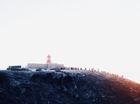 A crowd of people gathered on a high rocky hill to enjoy the beautiful golden hour