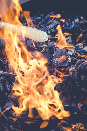 A vertical shot of food on a stick cooking on the fireの写真素材