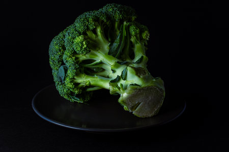 A fresh broccoli on a round glassy stand isolated on the black backgroundの写真素材