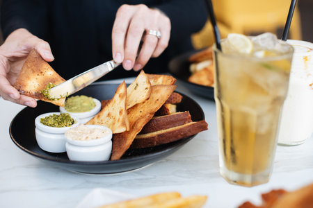 A selective closeup shot of a person spreading sauce on nachos