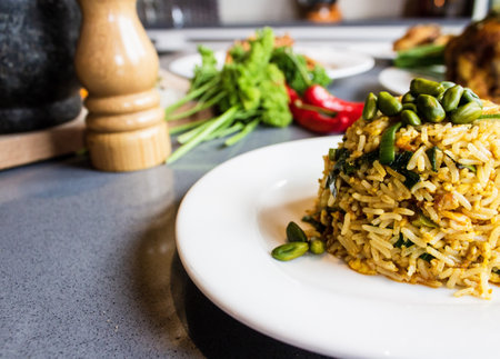 A closeup of rice with green pistachios on a round white plate with a blurred backgroundの写真素材
