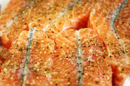 A closeup of salmon flavored with different spicesの写真素材