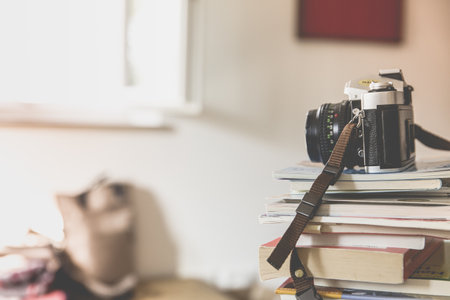 A black film camera on top of piled books inside a well-lighted roomの写真素材