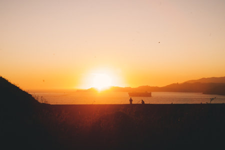A beautiful shot of the sunset at the beach with two people in thereの写真素材