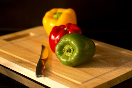 Preparing three colorful peppers on on cutting board for a healthy recipeの写真素材