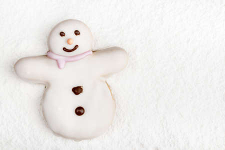 A high angle shot of a christmas cookie in the shape of a white snowman on a flour covered surfaceの写真素材