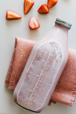 A closeup shot of glass bottle with tasty strawberry milkshake in itの写真素材