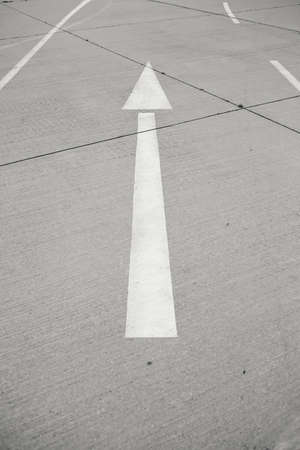 A vertical shot of a oneway street with an arrow drawn on it at daytimeの写真素材