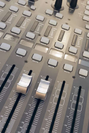 A high angle closeup shot of a grey professional sound mixer with two volume knobs pulled high