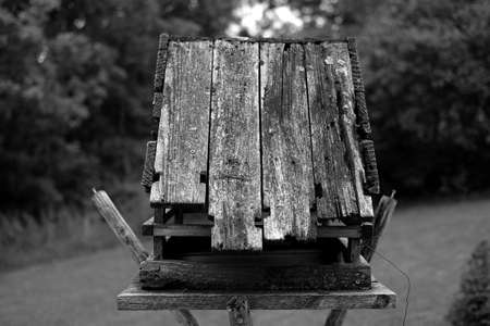 A greyscale shot of an old wooden birdhouse in a park