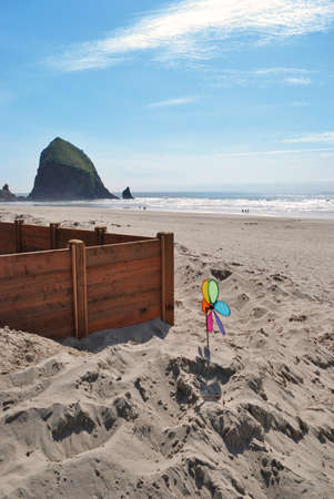 A rainbow colored windmill sits in the sand and wind at Cannon Beach, in Oregon, with Haystack Rock in the background.の写真素材