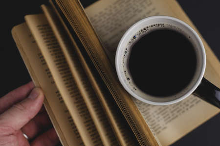 A high angle shot of a cup of coffee and an open book on the tableの写真素材