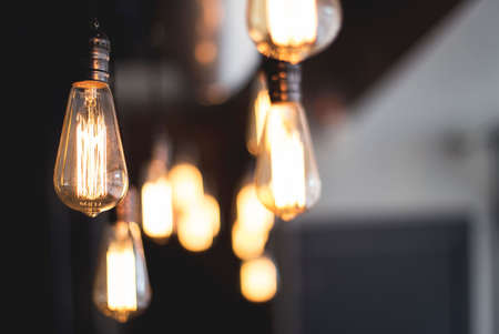 A wide selective closeup shot of illuminated light bulbs hanging from a ceiling