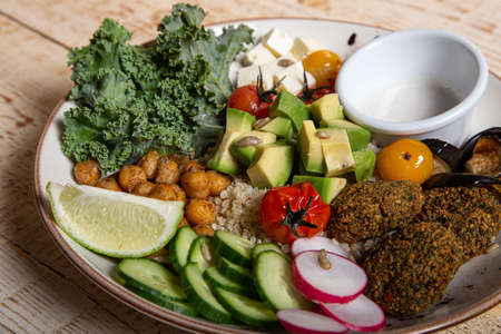 A plate of fresh vegetables and avocados on a wooden tableの写真素材