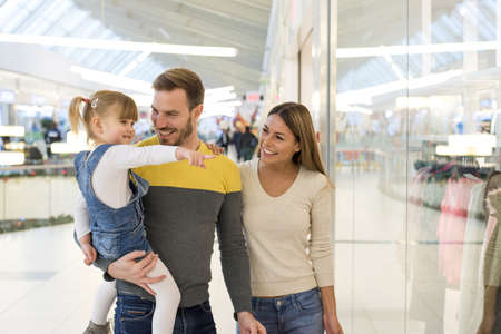 A beautiful couple doing shopping with their daughter in a shopping centreの写真素材