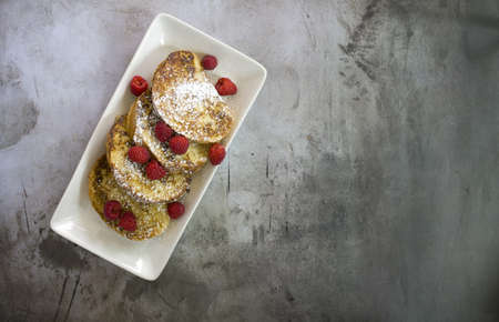 A high angle view of toasts with sugar powder and raspberries in a plate on the tableの写真素材