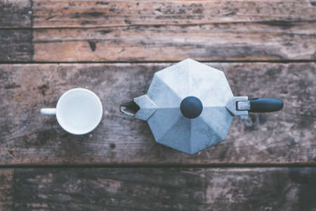 An overhead closeup shot of a white mug next to a gray teapot on a wooden backgroundの写真素材