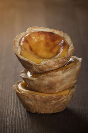 A vertical closeup shot of three homemade Caramel muffins on top of each other on a wooden surface