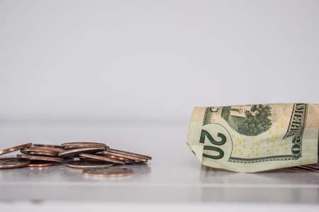 A closeup shot of pennies and a twenty-dollar bill on a white surface