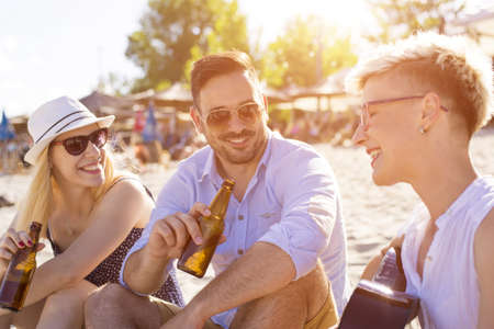 A group of Caucasian friends having fun on a sandy beachの写真素材