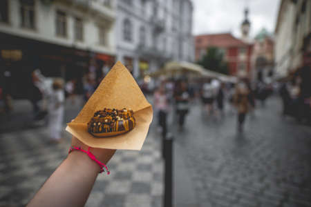 A closeup shot of a person holding a chocolate doughnutの写真素材