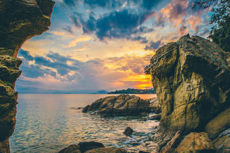 A beautiful wide shot of rock formation by the sea during golden hourの写真素材