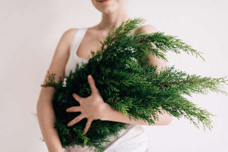 A close shot of a female holding a pine tree branches with a blurred backgroundの写真素材