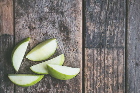 A closeup overhead shot of a sliced green apple on a wooden backgroundの写真素材