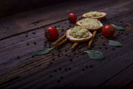 A closeup shot of bruschetta with avocado mousse, cherry tomatoes and basil leaves on rustic wooden...
