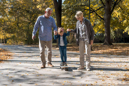 A beautiful picture of grandparents with their grandchild in the parkの写真素材