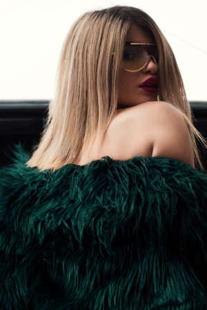 An attractive female model wearing a green fur dress and gold-framed sunglassesの写真素材
