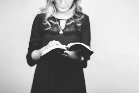 A vertical greyscale of a woman reading a book against a white background