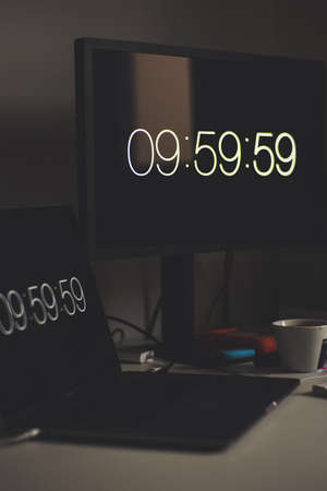 A vertical selective shot of a black laptop with time showing 09:59:59 on its screen