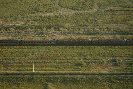 An aerial shot of an old rusty train on an abandoned railway