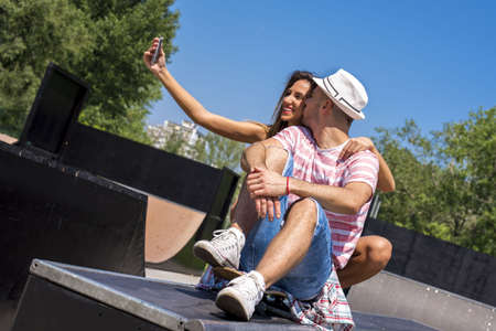A beautiful young couple having fun in a skate parkの写真素材