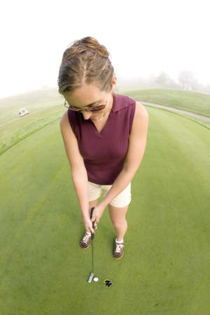 A vertical shot of a Caucasian young woman playing golf in the golf fieldの写真素材