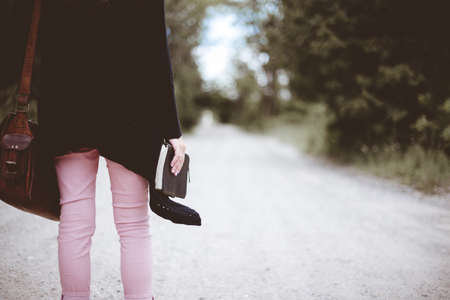 A selective closeup shot of a female wearing black jacket and a brown bag holding thick notebook...