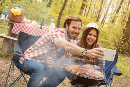 A Caucasian couple taking a selfie while having a picnic in the natureの写真素材