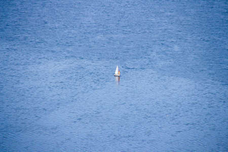 An aerial shot of a boat sailing in the empty sea at daytime