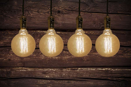 A closeup shot of vintage yellow lightbulbs symmetrically lined up next to each other on wooden...