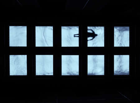 The abstract shot of blue watery windows with a silhouette of a person visible in them