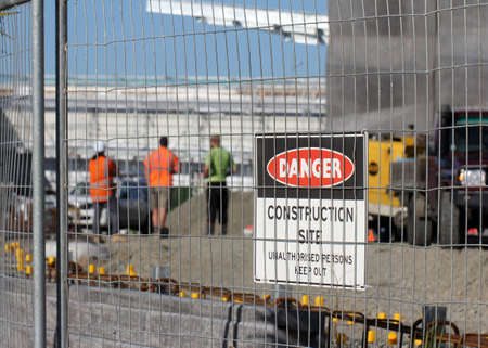 Men in high vis on a construction site with warning sign