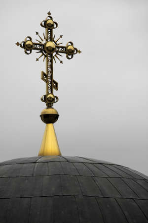 A vertical closeup of a golden decorated cross on a black church dome. Perfect for a religious...