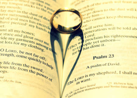 A closeup shot of a wedding ring on the Bible making a beautiful heart illustration