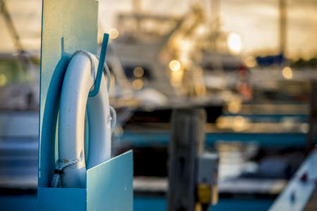 A closeup shot of a lifebuoy hanged on a column with bokeh lights in the backgroundの写真素材