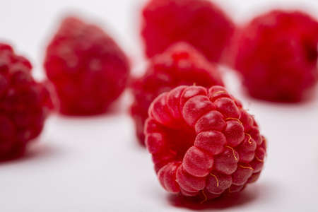 A closeup shot of fresh raspberries spread on a white background - perfect for a food blogの写真素材