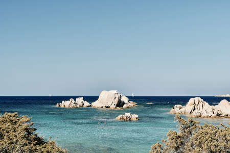 A beautiful shot of rocks in the sea with a blue sky in the background at daytime