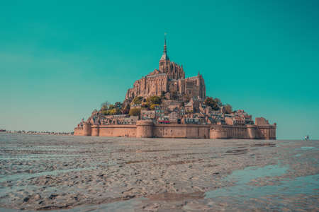 A low angle shot of a beautiful castle on wet sand with the turquoise sky in the backgroundの写真素材