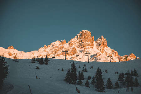 A beautiful shot of a snowy brown mountain with ski lifts alongside its base. Perfect for wallpaper
